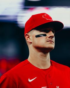 a close up of a baseball player wearing a red hat and black eyeliners