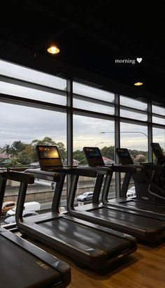 there are treadmills in the gym with windows looking out on the city below