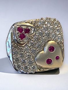 "Estate 14k White Gold BIG and BOLD 2 CTW Diamond Ruby Statement Heart Ring GORGEOUS! This beautiful vintage ring is sure to become a treasured heirloom! * Crafted with intricate detail, the beautiful large square face is a encrusted with beautiful round bright diamonds! * Ring face measures approximately 3/4\" across! * Round cut rubies are set into the hearts on face. * There are twenty nine (29) approximately .06 ct round diamonds set flush in this large square face ring! There are a total of Vintage Multi-stone Diamond White Rings, Vintage White Gold Multi-stone Diamond Ring, Vintage Multi-stone Diamond Ring In White Gold, Heirloom Style Valentine's Day Jewelry Ring, Valentine's Day Heirloom Ring Jewelry, Valentine's Day Heirloom Ring, White Hallmarked Diamond Ring Collectible, Heart-shaped Hallmarked Diamond Ring, 14k Heart Cut Diamond Ring For Valentine's Day