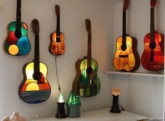 several guitars are hanging on the wall with stained glass windows behind them, along with other musical instruments