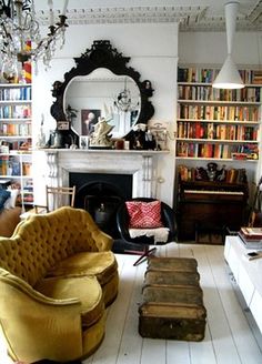 a living room filled with lots of furniture and bookshelves next to a fire place