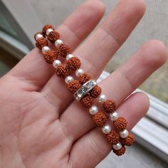 "Available in two sizes  6.5 inches - Fits a woman's  small to medium wrist.  7.5 Inches - Fits a woman's large wrist  Matching earrings available here: https://www.etsy.com/listing/796863122/rudraksha-rhinestone-and-swarovski-pearl The pearls used in this piece are faux. This shop only uses vegan materials. Pearls are Swarovski Crystal and feature an alabaster hue for an elegant design appeal. At the heart of each Swarovski pearl lies a solid core of Swarovski crystal, which is covered in layers of innovative pearlescent \"nacre\" to create a flawless silky smooth surface that resists cosmetics, chemicals, and perfumes.  It is said that Rudraksha seeds are the tears of compassion shed by Hindu God Shiva when He turned His divine gaze towards humanity and was moved by the suffering. Shiva' Adjustable Silver Beaded Bracelets, Spiritual Meditation Bracelets, Spiritual Round Beads Jewelry For Blessing, Spiritual Round Beads Bracelets For Meditation, Spiritual Gemstone Beaded Bracelets For Meditation, Spiritual Gemstone Beads Stretch Bracelet For Meditation, Spiritual Hand-strung Beaded Bracelets For Rituals, Spiritual Gemstone Beads Bracelet For Meditation, 8mm Beads Bracelet For Blessing