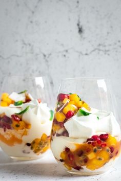 two glasses filled with fruit and whipped cream