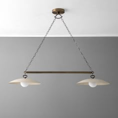 three lights hanging from a ceiling fixture in a room with white walls and gray flooring