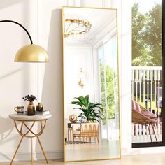 a mirror sitting on top of a wooden floor next to a table with a potted plant