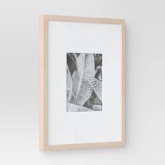 a black and white photo hanging on the wall next to a wooden frame with a plant in it