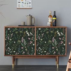 an old dresser with flowers painted on the side and two bottles sitting on top of it