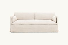 a white couch sitting on top of a white floor next to a wall with a light colored background