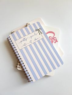 two notebooks sitting next to each other on top of a white table with writing on them