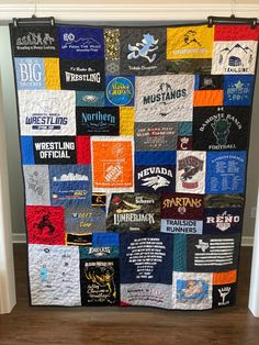 a quilt made to look like it has many different logos on it and is hanging up against the wall