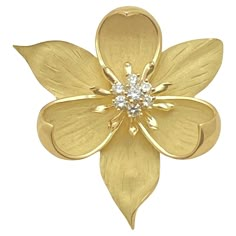 Dogwood flower blossom pendant brooch in 18 karat yellow gold with satin textured petals with curved up tips. The central pistil of the blossom is accented by seven round brilliant-cut diamonds weighing approximately 0.55 total carats. Polished underside has single pin stem with clasp and hidden bail top for chain to slide through, so it can be worn as a brooch or suspended on a neck chain to be worn as a pendant. Signed 'TIFFANY & CO'. 1.75" long. Tiffany Gold, Diamond Flower Pendant, Dogwood Flowers, Flowers Jewelry, Golden Jewelry, Jewelry Auction, Metal Flower, Diamond Flower, Floral Jewellery