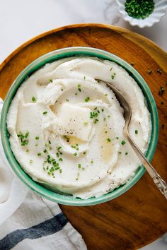 a bowl filled with mashed potatoes on top of a wooden cutting board