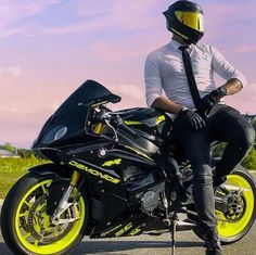 a man sitting on the back of a black and yellow motorcycle wearing a neck tie