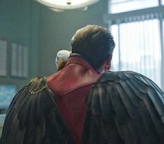 a man with a bald eagle on his shoulder in an office building looking out the window