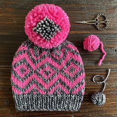 a pink and gray knitted hat with pom - pom