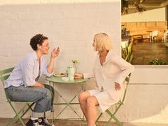 two people sitting at a table talking to each other