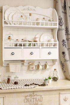 a white china cabinet filled with dishes and utensils on top of a counter