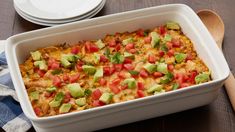 a casserole dish with tomatoes, avocado and other toppings