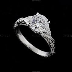 a white gold engagement ring with an old - fashioned style diamond center and filigrees