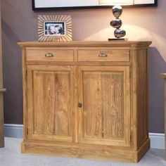 a wooden sideboard with two drawers and a lamp on top of it in a living room