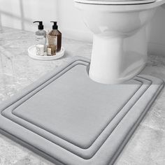 a white toilet sitting next to a bath tub and a sink in a bathroom with gray rugs