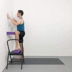 a man sitting on top of a chair in front of a wall with his hands up