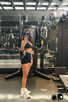 a woman taking a selfie in front of a gym equipment machine with her cell phone