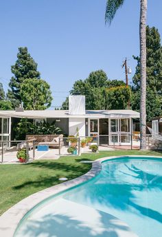 a house with a swimming pool in front of it and palm trees around the pool