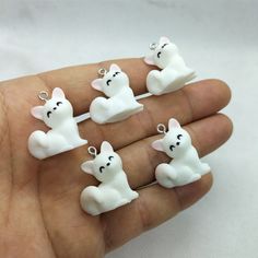 four small white dogs sitting on top of each other in the palm of someone's hand