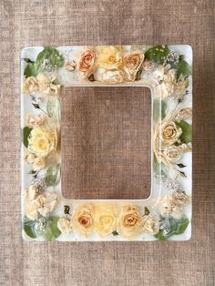 a white frame with yellow and orange flowers on the bottom is sitting on a brown surface