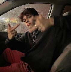 a woman sitting in the back seat of a car with her hand up and pointing at something