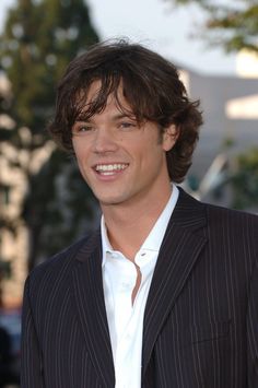 a man in a pinstripe suit smiles at the camera