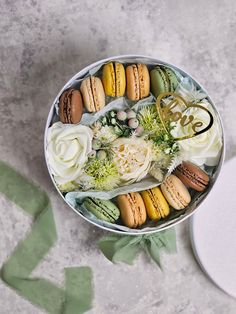 a tin filled with macaroons and flowers on top of a table