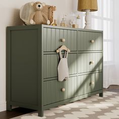 a green dresser with two teddy bears on the top and one stuffed animal hanging from it's handles