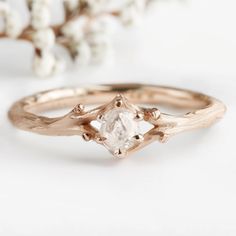 a rose cut diamond sits on top of a gold ring with branches in the background