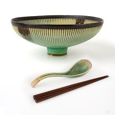 a green bowl with chopsticks next to it