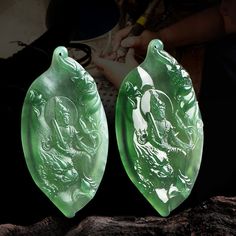 two green jade plaques sitting on top of a wooden table