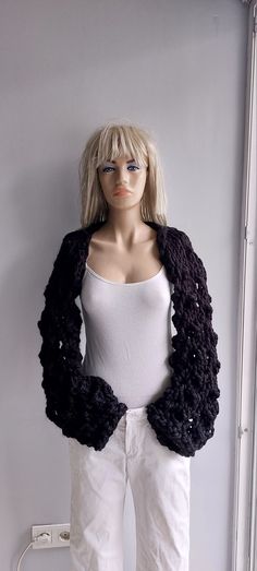 a female mannequin wearing white pants and a black knitted shrugr jacket