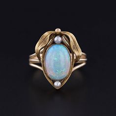 Antique Opal and Pearl Ring: This ring features a fiery white opal and two pearls mounted in 12ct gold.  The top of the ring was originally an antique stickpin (circa 1900) that our jeweler transformed by removing the pin and adding a 14k gold band. The face of the ring measures 0.8 inches by 0.6 inches wide, and it is in great condition.  The ring is a size 7, but it can be resized free of charge. Upon purchase, your ring will arrive elegantly packaged, ready for gifting or as a special treat for yourself.  We carefully wrap each piece to ensure a delightful unboxing experience. We also offer free and flexible layaway plans, so take advantage of this option to make owning your dream piece even more achievable. + Trademark Antiques Shop Homepage https://www.etsy.com/shop/TrademarkAntiques Antique Opal Ring, Bespoke Rings, Locket Charms, White Opal, Gold Band, Pearl Ring, Opal Rings, Rings Statement, Gold Bands