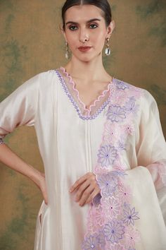 This refreshing ivory kurta set is the perfect addition to your festive wardrobe.
The chanderi kurta has pintuck detailing and delicate scalloped embroidery on neck and sleeves.It is paired with chanderi pants in ivory with delicate embroidery.
The silk organza dupatta has beautiful geometric floral embroidery in lavender and rosepink threadwork which adds a pop of colour to the classic design elevating the overall look. Elegant Anarkali Set With Embroidered Border For Spring, Elegant Spring Anarkali Set With Embroidered Border, Feminine Resham Embroidery Sets For Festive Occasions, White Churidar For Spring Festive Occasions, White Churidar For Festive Spring Occasions, White Churidar For Festive Spring Season, White Festive Churidar For Spring, Cream Straight Kurta Set With Sheer Dupatta, Cream Sets With Sheer Dupatta And Straight Kurta