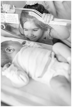 a woman reading a book to a baby laying on it's back in bed