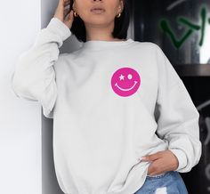 Bring happiness wherever you go with this super trendy starry eyed smiley face crewneck sweatshirt! Featuring a bold, simple, hot pink graphic, this piece is perfect to finish off your trendy, oversized look! Makes a great gift for a friend, or for yourself! Please note: This item is PRINTED, not embroidered. Printed on a soft, cotton-poly blend Gildan sweatshirt. SIZING: Our sweatshirts are unisex sizing. We suggest ordering your normal size for a regular fit. If you want an oversized fit we su Trendy Relaxed Fit Sweatshirt, Trendy Relaxed Fit Sweatshirt With Screen Print, Trendy Long Sleeve Sweatshirt With Funny Print, Trendy Crew Neck Sweatshirt, Trendy Screen Print Sweatshirt For Loungewear, Trendy Crew Neck Sweater With Screen Print, Relaxed Fit Smiley Face Top For Loungewear, Trendy Smiley Face Loungewear Tops, Trendy Smiley Face Tops For Loungewear