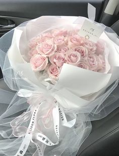 a bouquet of pink roses is wrapped in clear cellophane and sits on the front seat of a car