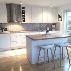 a kitchen with two stools next to an island in the middle of the room