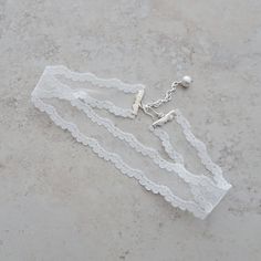 "This lovely ivory soft vintage lace choker necklace is made up in a scalloped and netted pattern. The lace portion of the choker is crimped with silver bars and there is an adjustable length of 13 1/2\" - 15\" with the extension chain accented with a glass pearl bead. There is a silver hook closure. The width of the lace is 1 \". If you need a different neck measurement I can make this choker to your length requirement. Just send me a message with your order and I will customize size for you. A Elegant Lace Wedding Choker, Adjustable Pearl White Choker For Wedding, Feminine Adjustable Choker For Wedding, Delicate White Choker For Wedding, Wedding Lace Trim Choker Jewelry, White Lace Wedding Choker, Delicate White Wedding Choker, Vintage Lace Jewelry For Weddings, Lace Choker With Lace Trim As Gift