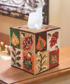 a tissue dispenser made out of bead and fabric with autumn leaves on it