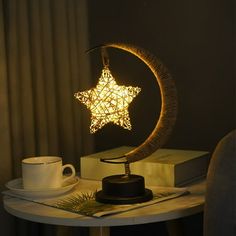 a table with a lamp that has a star on it and a cup next to it