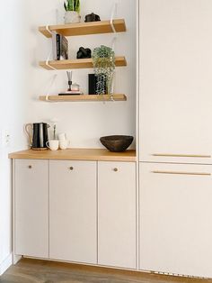 a kitchen with white cabinets and wooden shelves