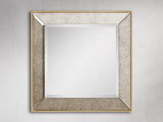 a square mirror hanging on the wall with a gold border around it and a white background