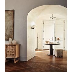 an archway leading into a living room with wood floors and white walls, along with a round dining table